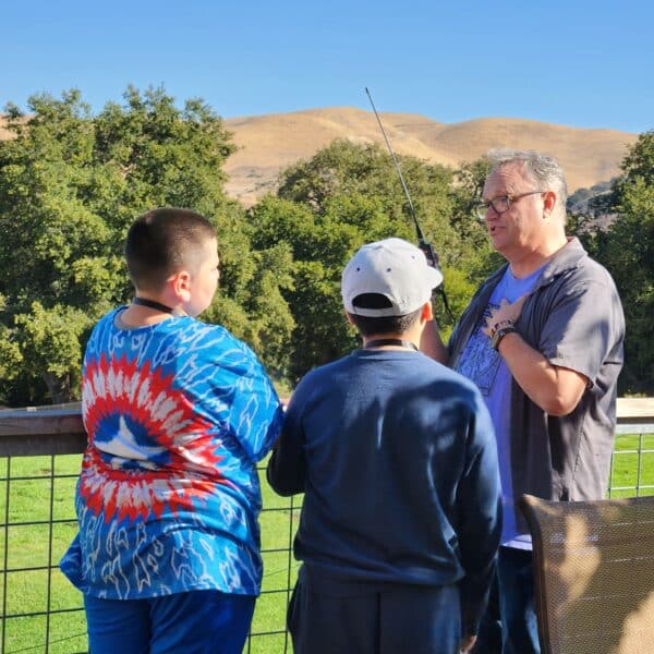 Spencer Holmes KM6SJ shows how to use an handheld amatuer radio to students at Camp Family Justice