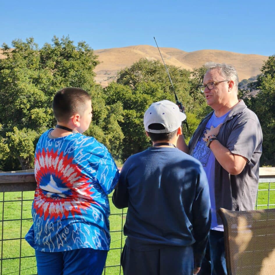 Spencer Holmes KM6SJ shows how to use an handheld amatuer radio to students at Camp Family Justice